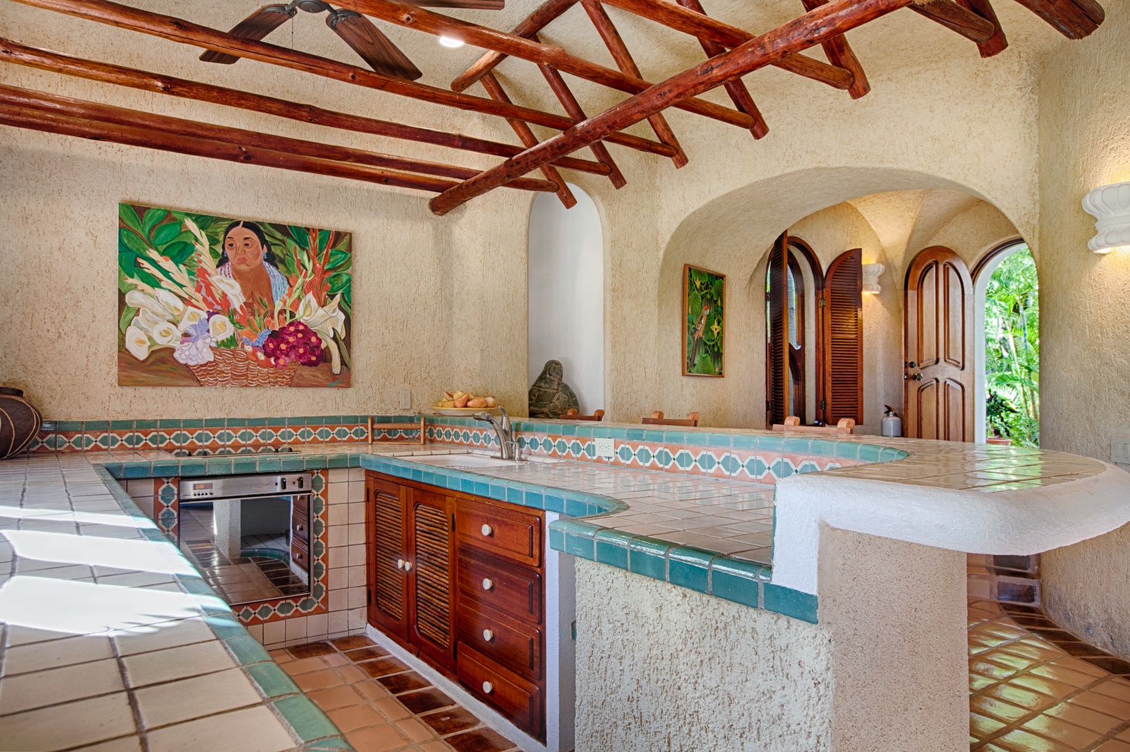 Cook in your stunning Mexican-inspired kitchen with colorful tile work, exposed wooden beams, and tropical artwork creating an authentic hacienda atmosphere.