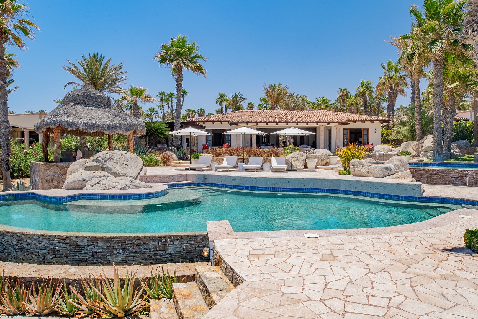 Stunning luxury villa showcasing pristine swimming pool, tropical palms, and elegant outdoor spaces in a desert oasis setting.