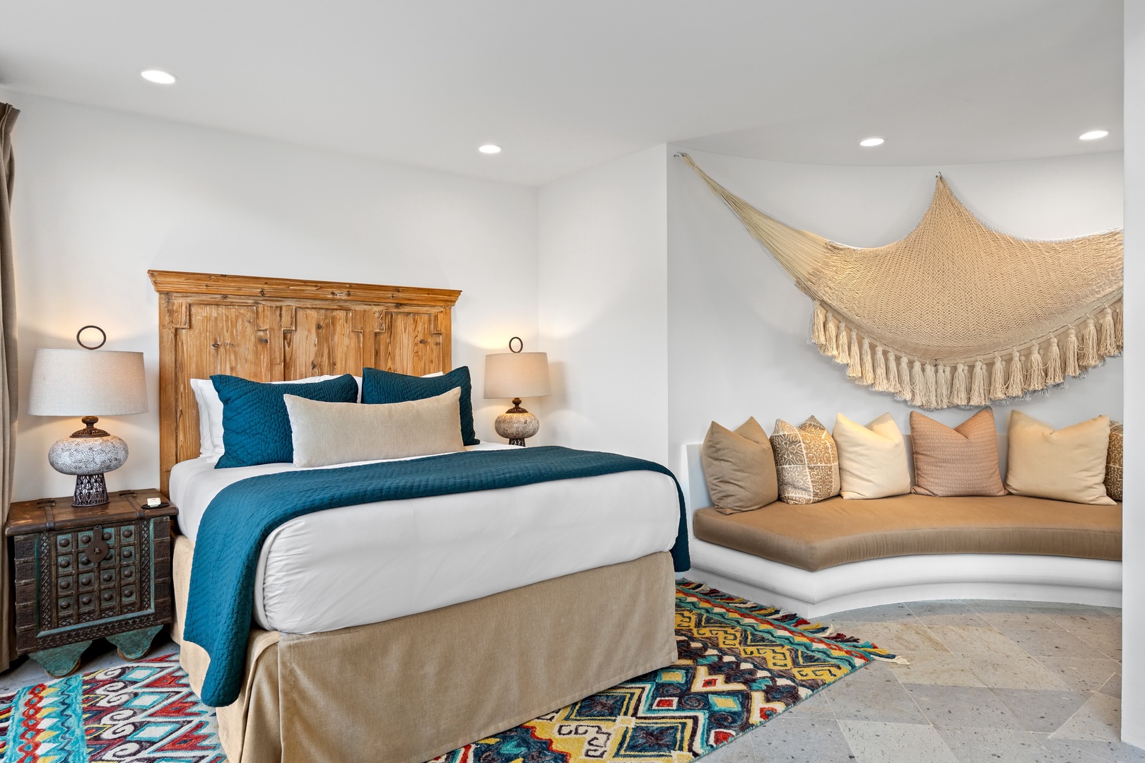 Sink into plush bedding while your built-in seating nook beckons for morning coffee or evening relaxation under handwoven textures.