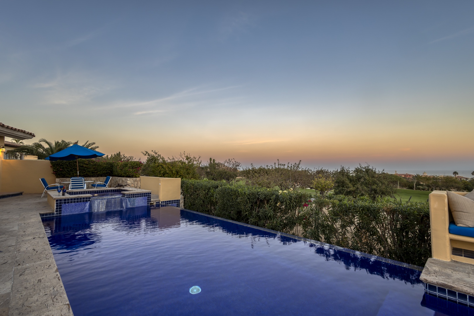 Private infinity pool overlooking lush landscape during golden hour twilight at this peaceful resort property.