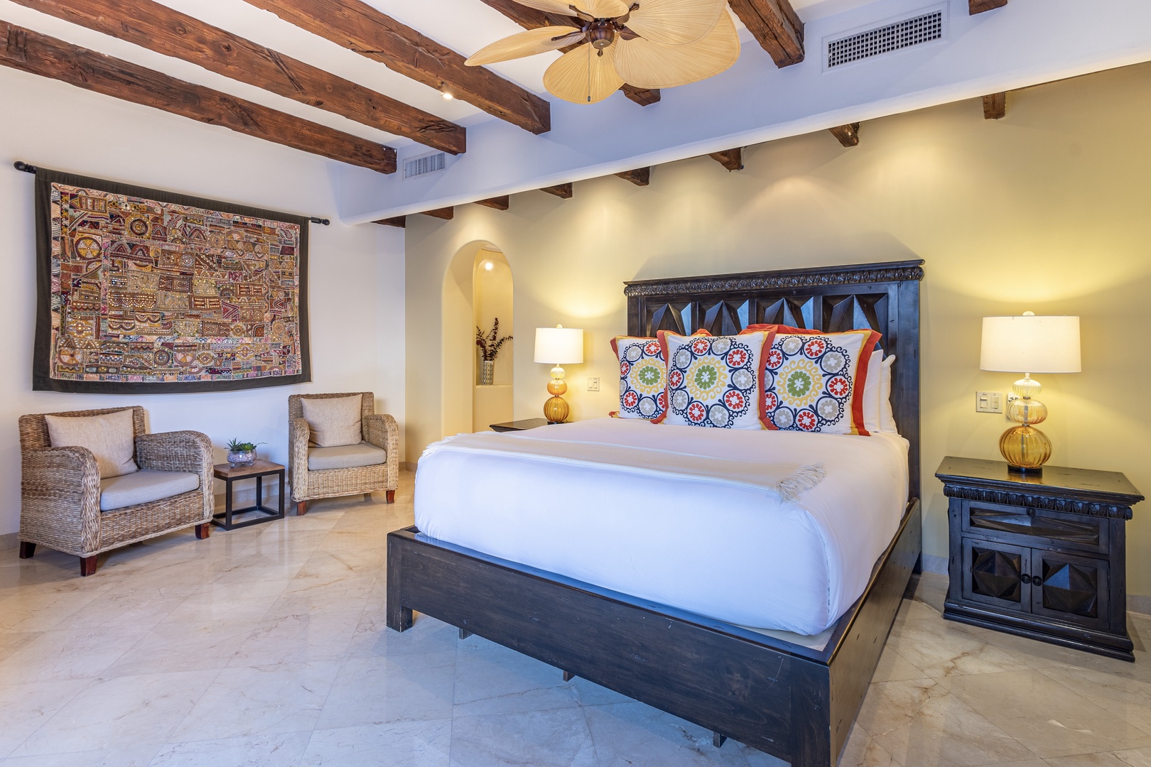 Your spacious retreat features exposed wood beams, elegant furnishings, and a plush king bed dressed in vibrant textiles. Sink into the woven seating area and unwind beneath soft lighting.