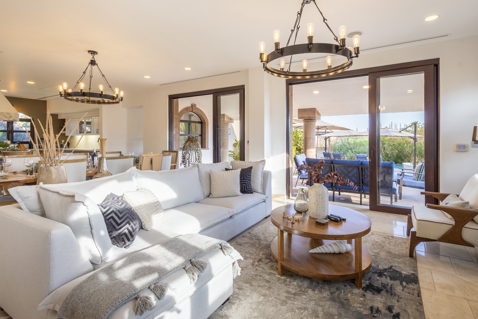 Sink into plush sofas in your elegant living room, where rustic chandeliers and sunlit glass doors open to your private patio—a perfect space to unwind and connect.
