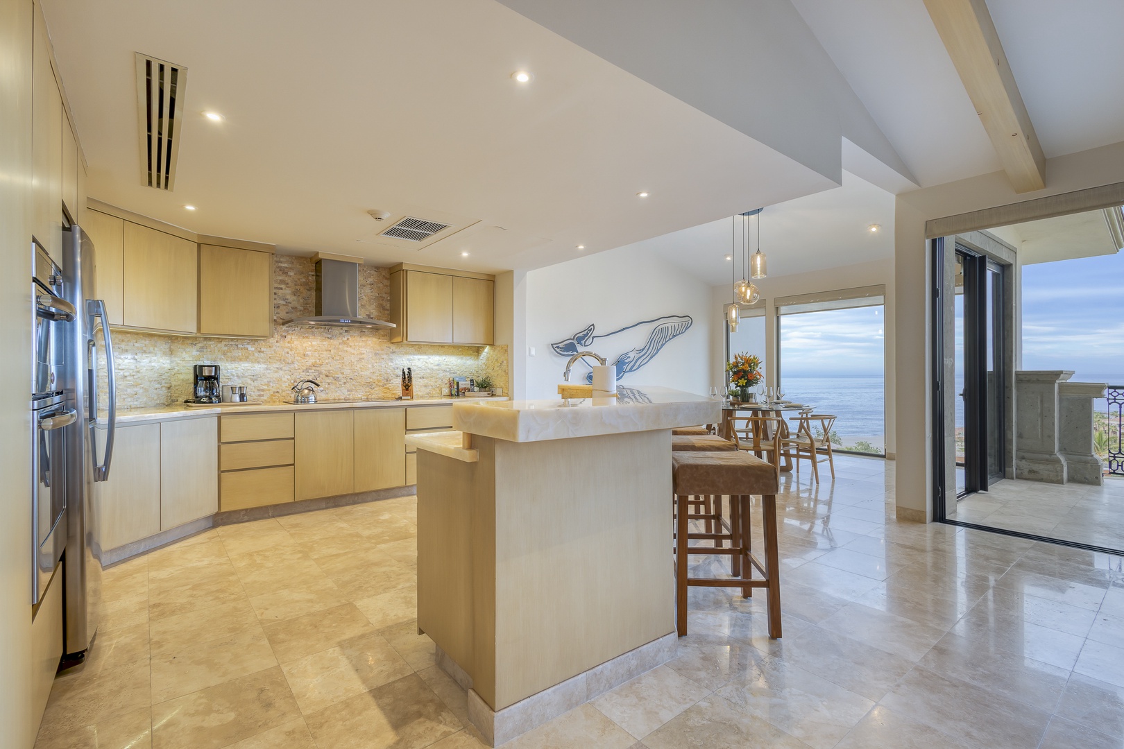Cook your favorite meals in this bright, modern kitchen while gazing out at stunning ocean views through floor-to-ceiling windows. The sleek island invites you to gather and savor every moment.