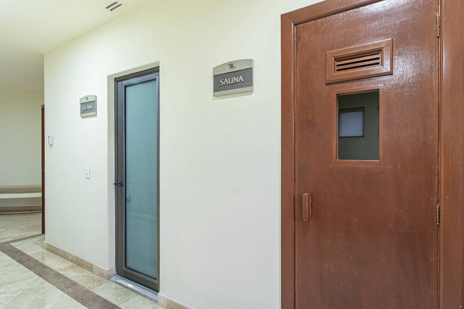 The building features wellness facilities including a steam room and sauna, accessible via this clean, well-maintained hallway where relaxation awaits.