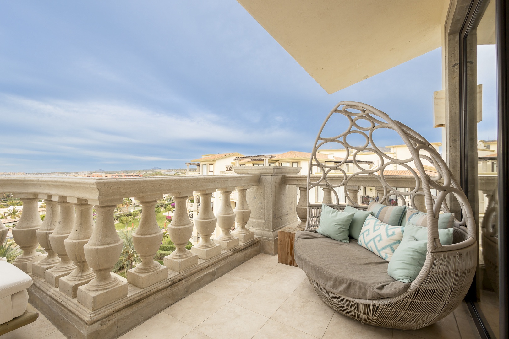 Unwind in your private balcony's cocoon daybed, surrounded by elegant balustrade detailing and sweeping desert views that stretch to the horizon.