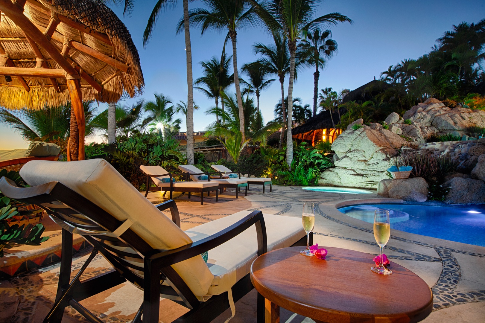 Unwind in your tropical paradise with champagne by the sparkling pool as palm trees sway overhead in the warm evening breeze.