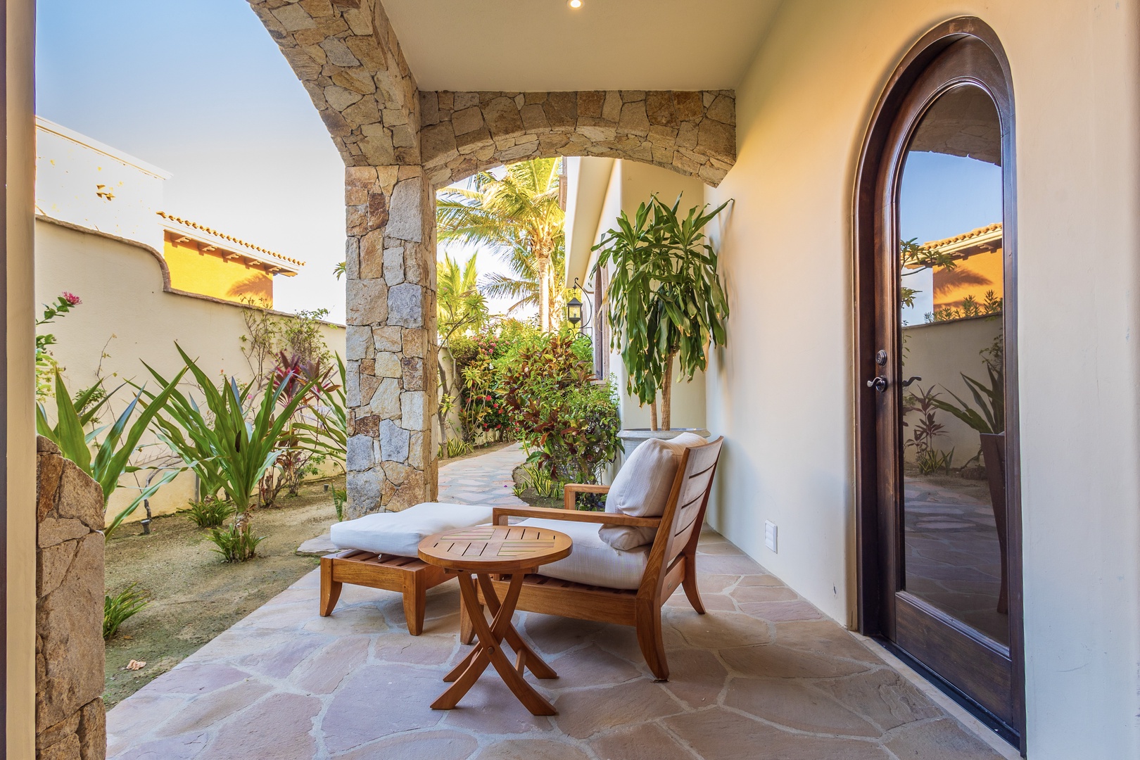 Your private outdoor sanctuary features elegant stone archways, lush tropical plants, and inviting lounge seating—perfect for morning coffee or unwinding after a day of adventure.