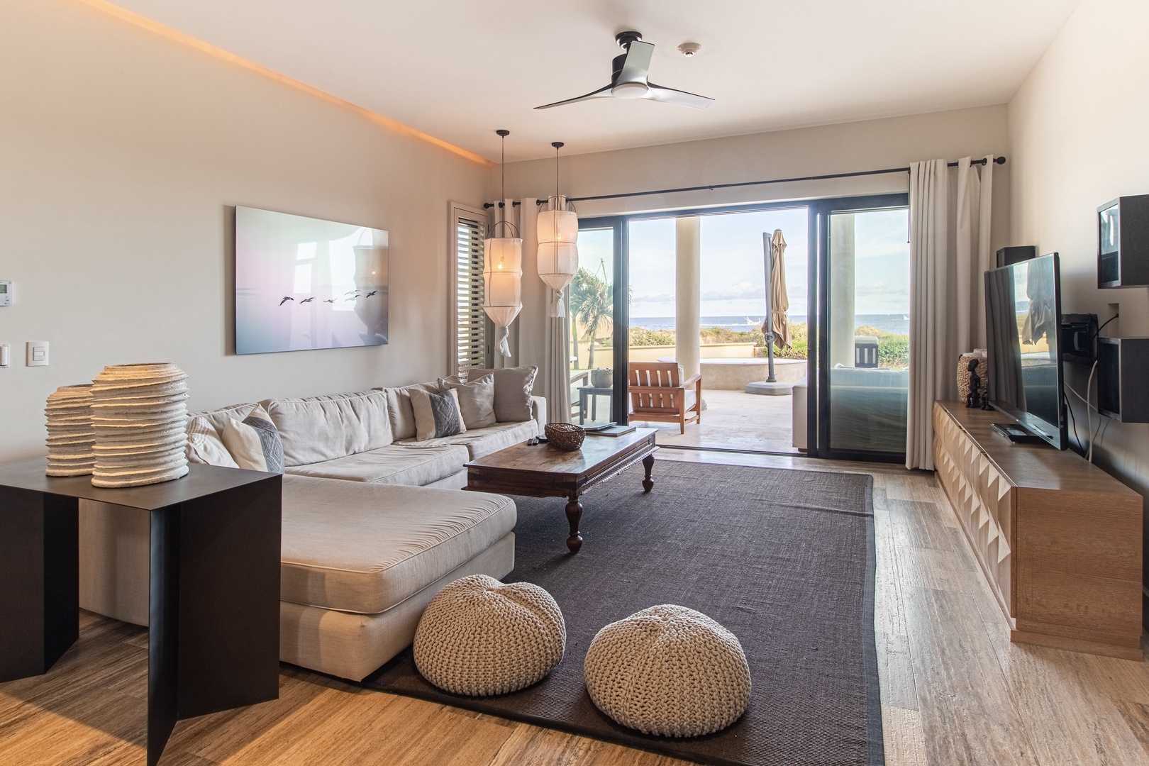 Settle into this bright living room where neutral tones and plush seating invite you to unwind. Through the glass doors, your private terrace awaits with coastal views.