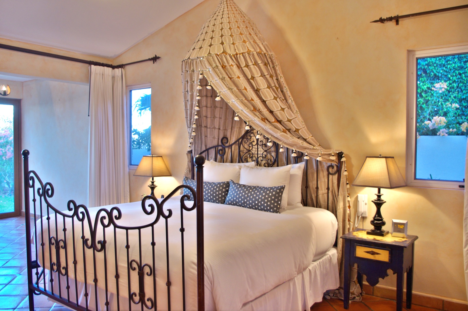 Picture yourself drifting to sleep under this romantic canopy, wrapped in crisp white linens. Warm lighting and elegant wrought-iron details create your private sanctuary for pure relaxation.