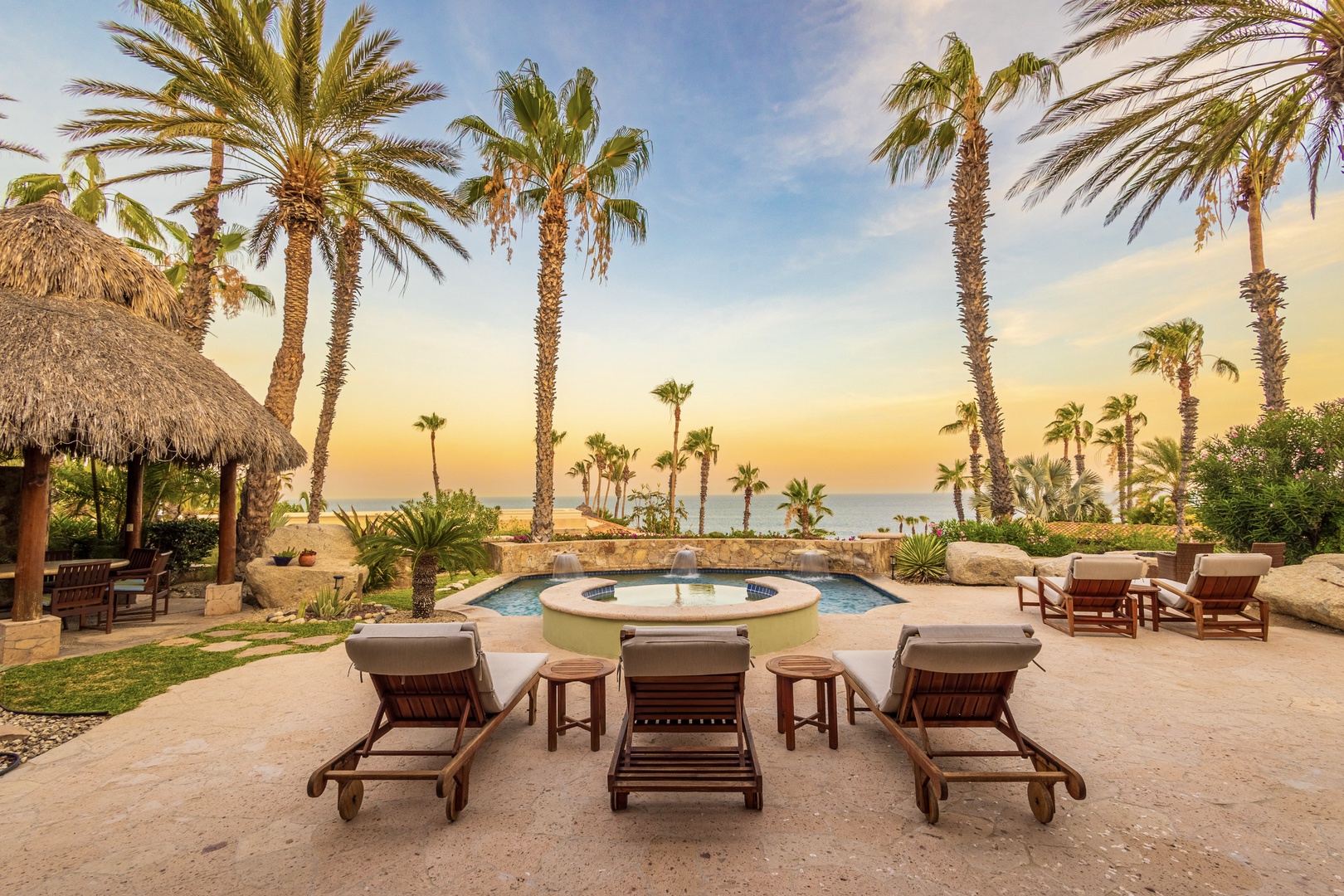 Tropical paradise awaits with towering palms framing a peaceful fountain and loungers just steps from the water. Picture yourself unwinding here as the ocean breeze and golden sunset set the perfect tone for your escape.
