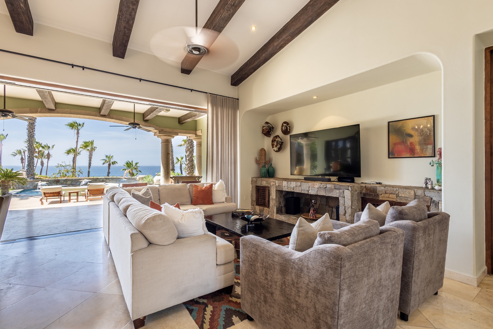 Unwind in your elegant living room where rustic beams meet modern luxury, with ocean views framing your relaxation space.