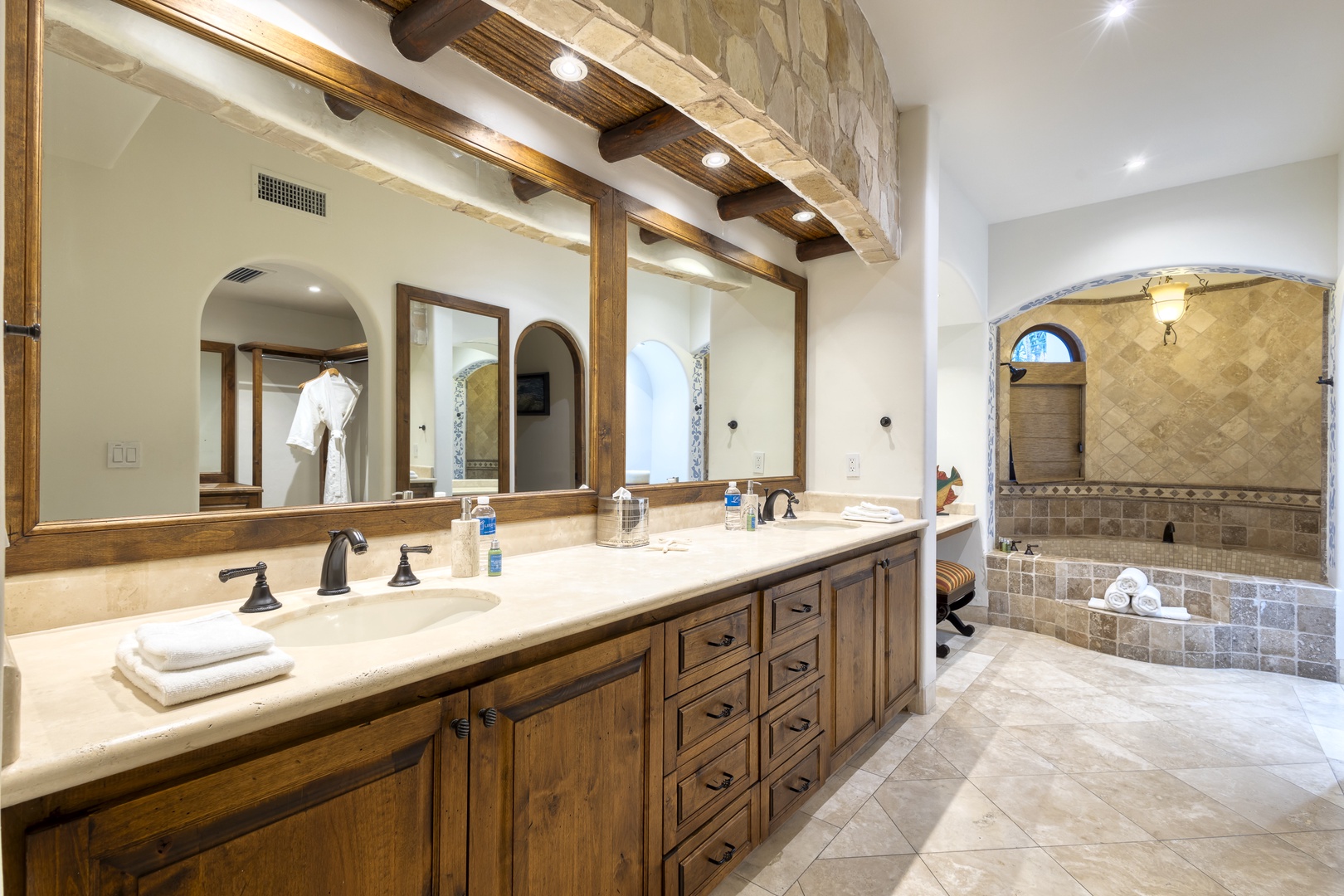 Unwind in your luxurious master bathroom featuring dual vanities, exposed wood beams, and a stunning stone-tiled soaking tub perfect for relaxing evenings.