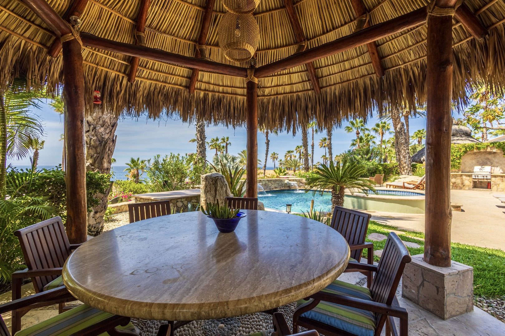 This thatched palapa frames a tropical oasis where you'll find your private pool gleaming beyond lush palms and desert gardens, with the shimmering ocean just beyond.