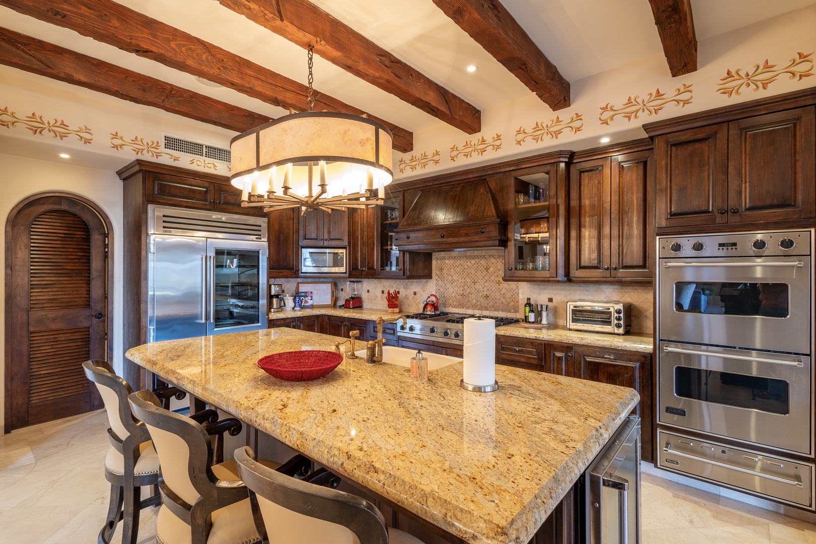 Gather around the spacious granite island in your gourmet kitchen, where exposed wood beams and elegant finishes create a warm, inviting space for cooking and connecting with loved ones.