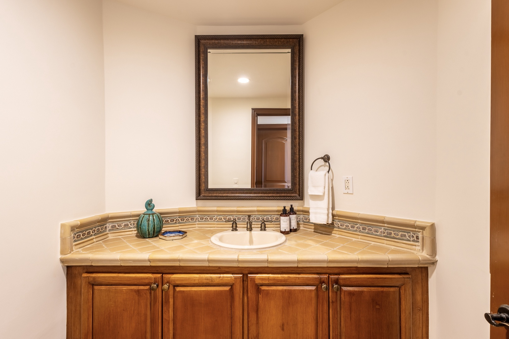 Refresh at your elegant vanity with tile counters and warm wood cabinets, thoughtfully stocked with amenities for your comfort.