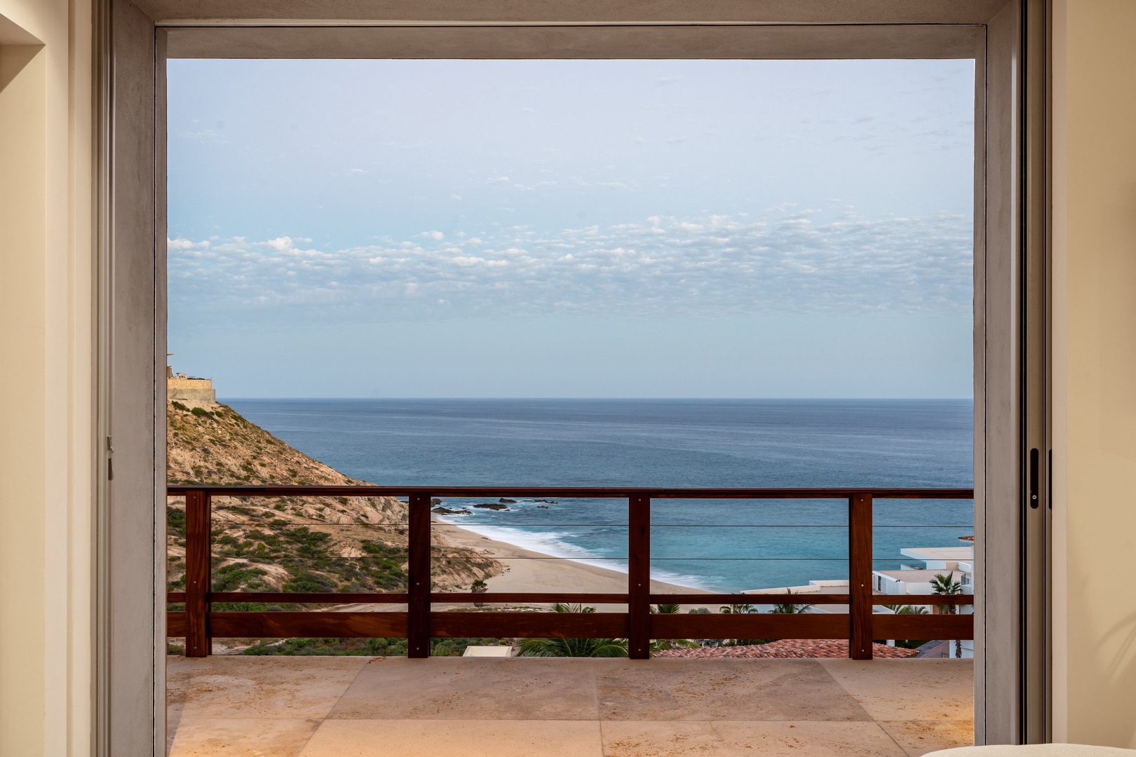 Step onto your private balcony and gaze out at endless ocean views stretching to the horizon, with rugged coastline and sandy beach below.