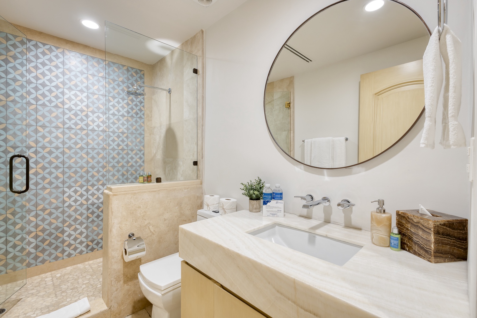 Step into your private spa-like bathroom featuring soft neutral tones and a stunning geometric-tiled walk-in shower. Fresh towels and thoughtful details await your arrival.