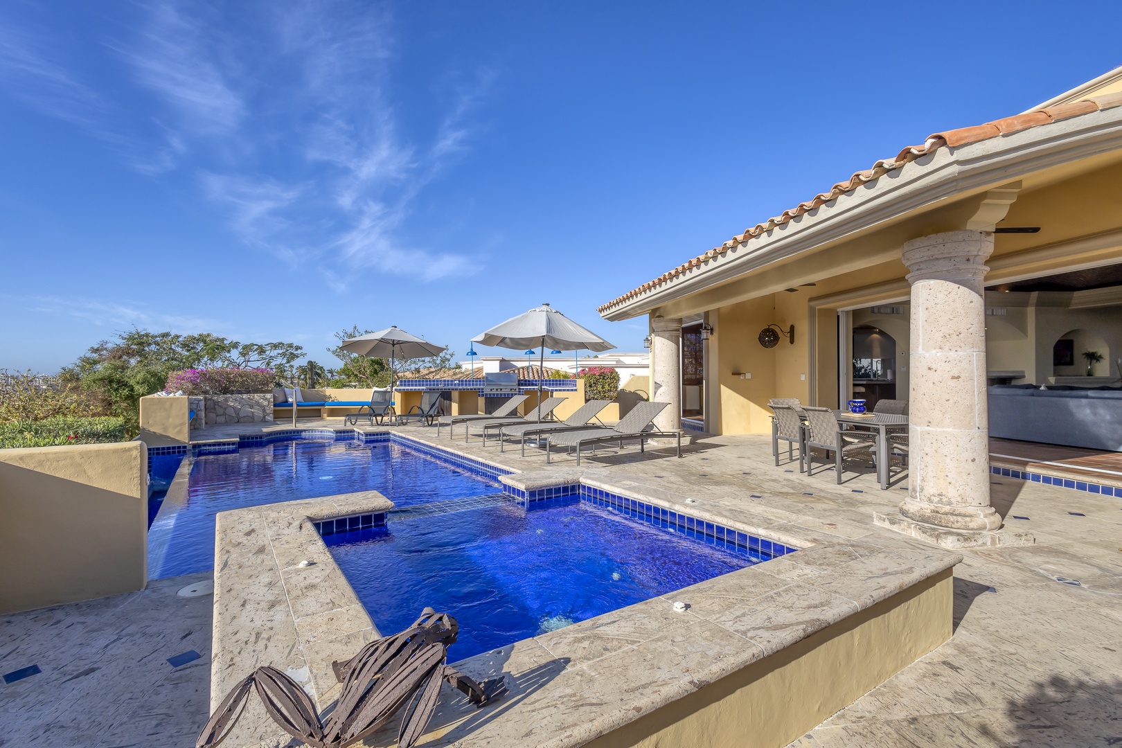 Stunning villa pool deck with crystal blue waters and covered terrace - perfect for lounging under warm skies.
