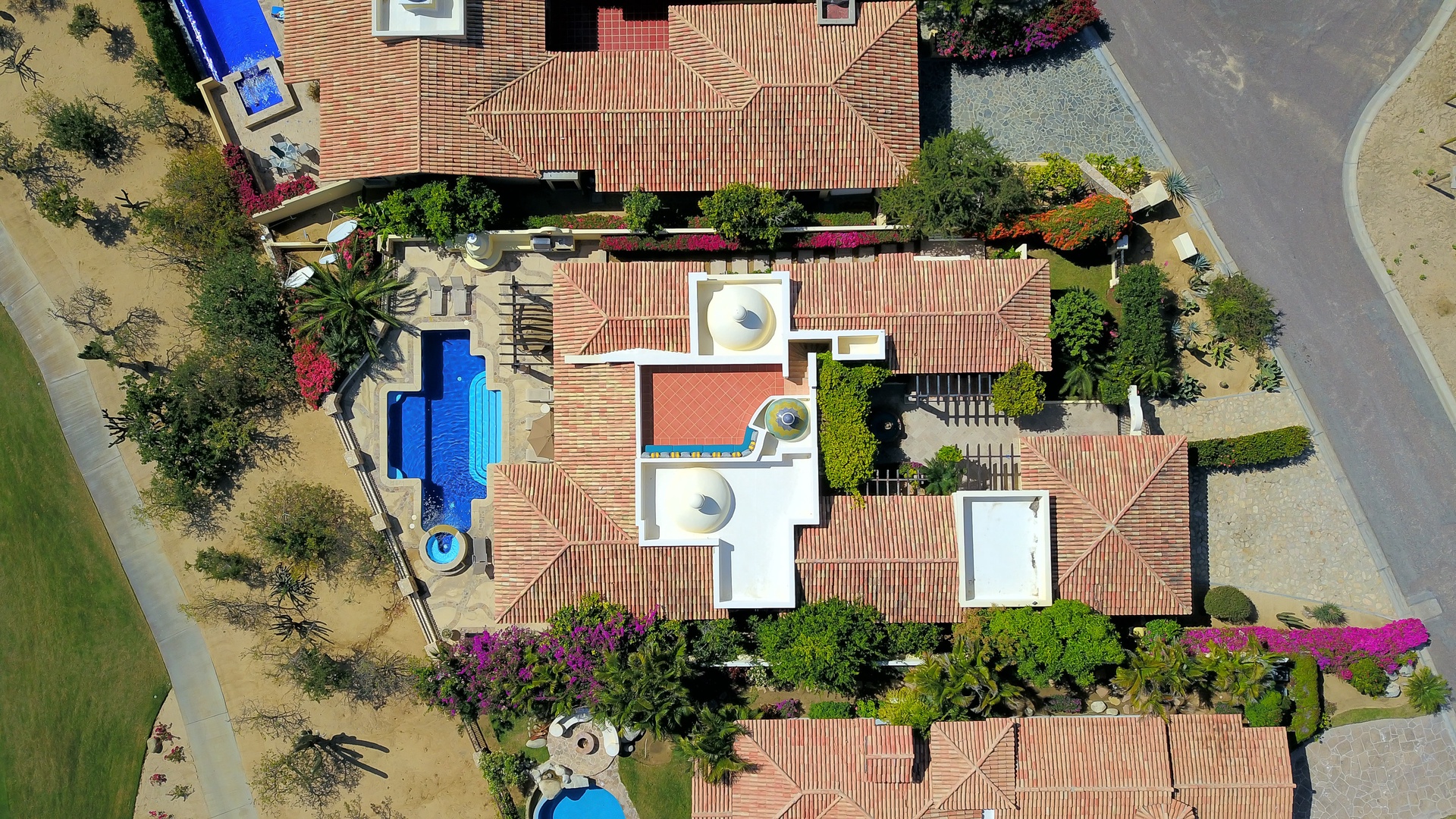 Stunning aerial view of a luxury villa complex with Mediterranean-style terracotta rooftops, swimming pools, and landscaped gardens.