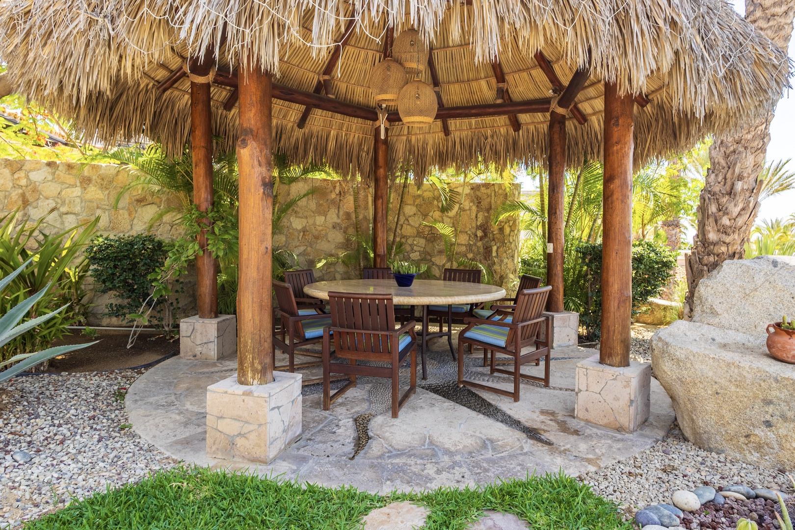 Picture yourself gathering around this shaded dining table, surrounded by lush palms and tropical greenery—your own private palapa for alfresco meals under gently rustling thatch.