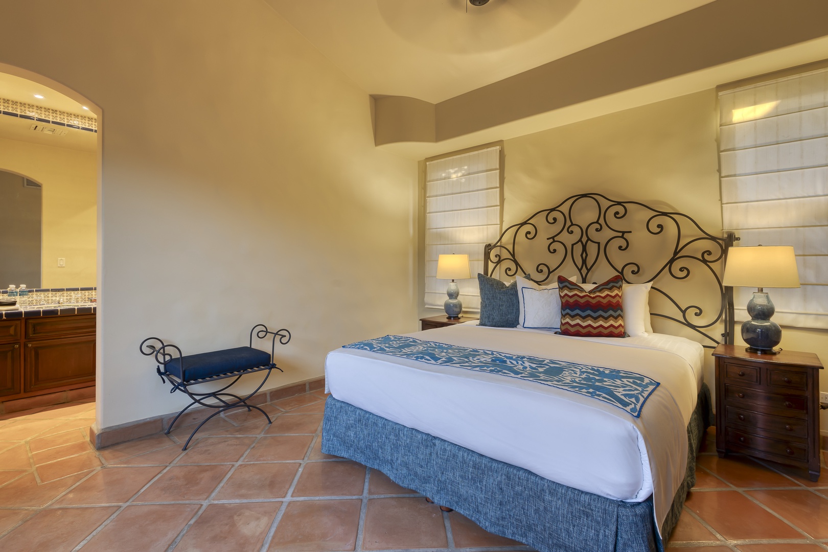 Sink into your king-size sanctuary with handcrafted iron headboard, crisp linens, and warm terracotta tiles underfoot.