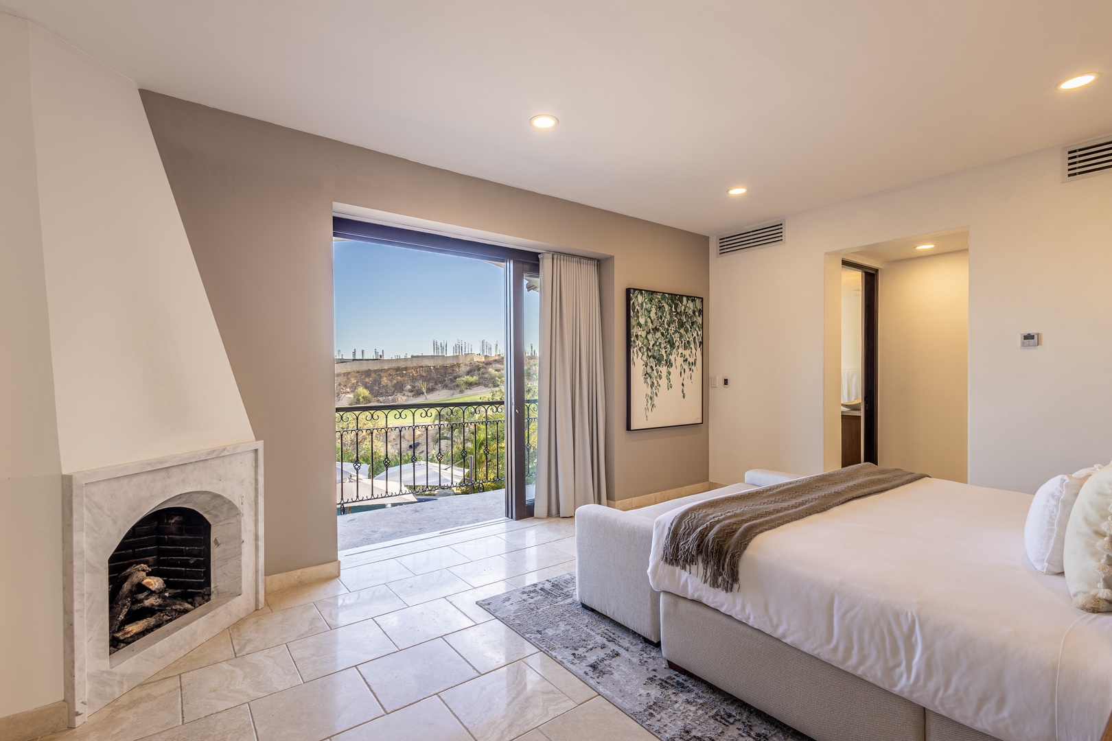 Wake up to natural light streaming through your private balcony doors, where city and landscape views blend beautifully. A cozy fireplace adds warmth to your bright, serene bedroom retreat.