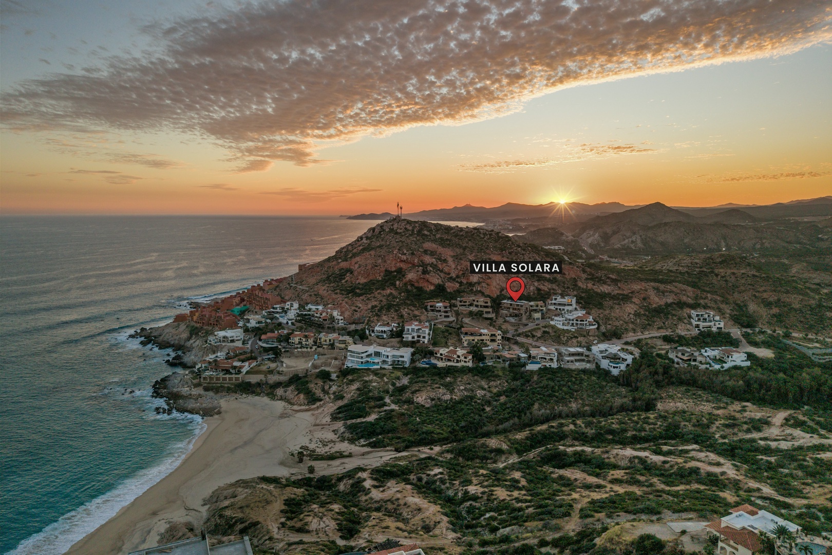 Aerial view of the coastal neighborhood at sunset, showcasing the property's hillside location near beaches and ocean views.