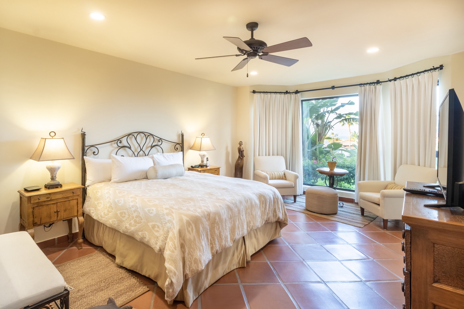 Sink into crisp linens and enjoy garden views from your cozy seating area. This serene retreat features a ceiling fan, warm tile floors, and a flat-screen TV for your relaxation.