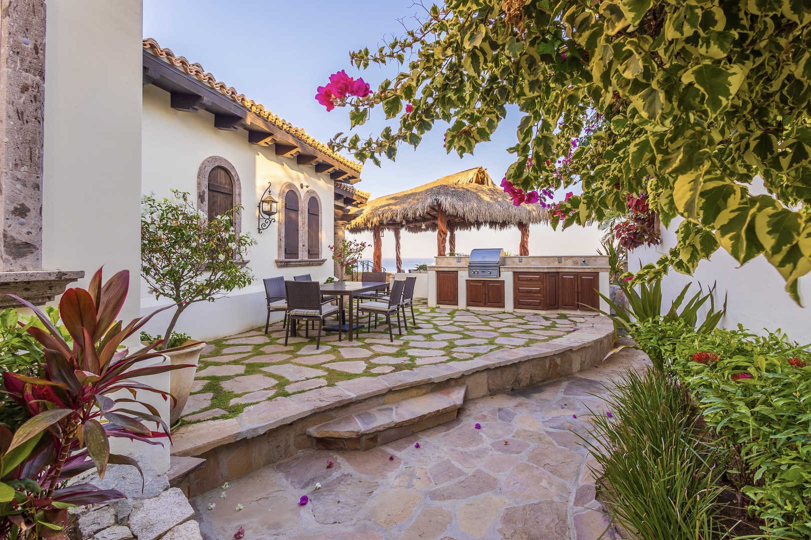 Imagine yourself in this private courtyard sanctuary where lush bougainvillea frames your outdoor kitchen, perfect for grilling fresh catches under swaying palms while sunset colors the sky.