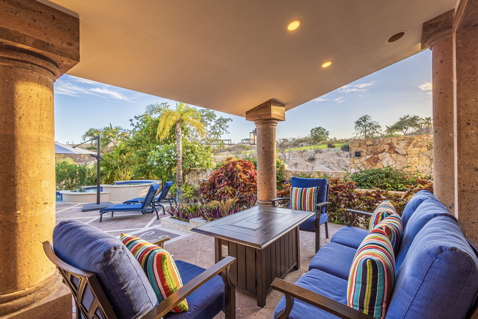 Unwind on your private covered patio with plush seating, vibrant cushions, and views of lush gardens and desert landscapes—your perfect spot to relax.