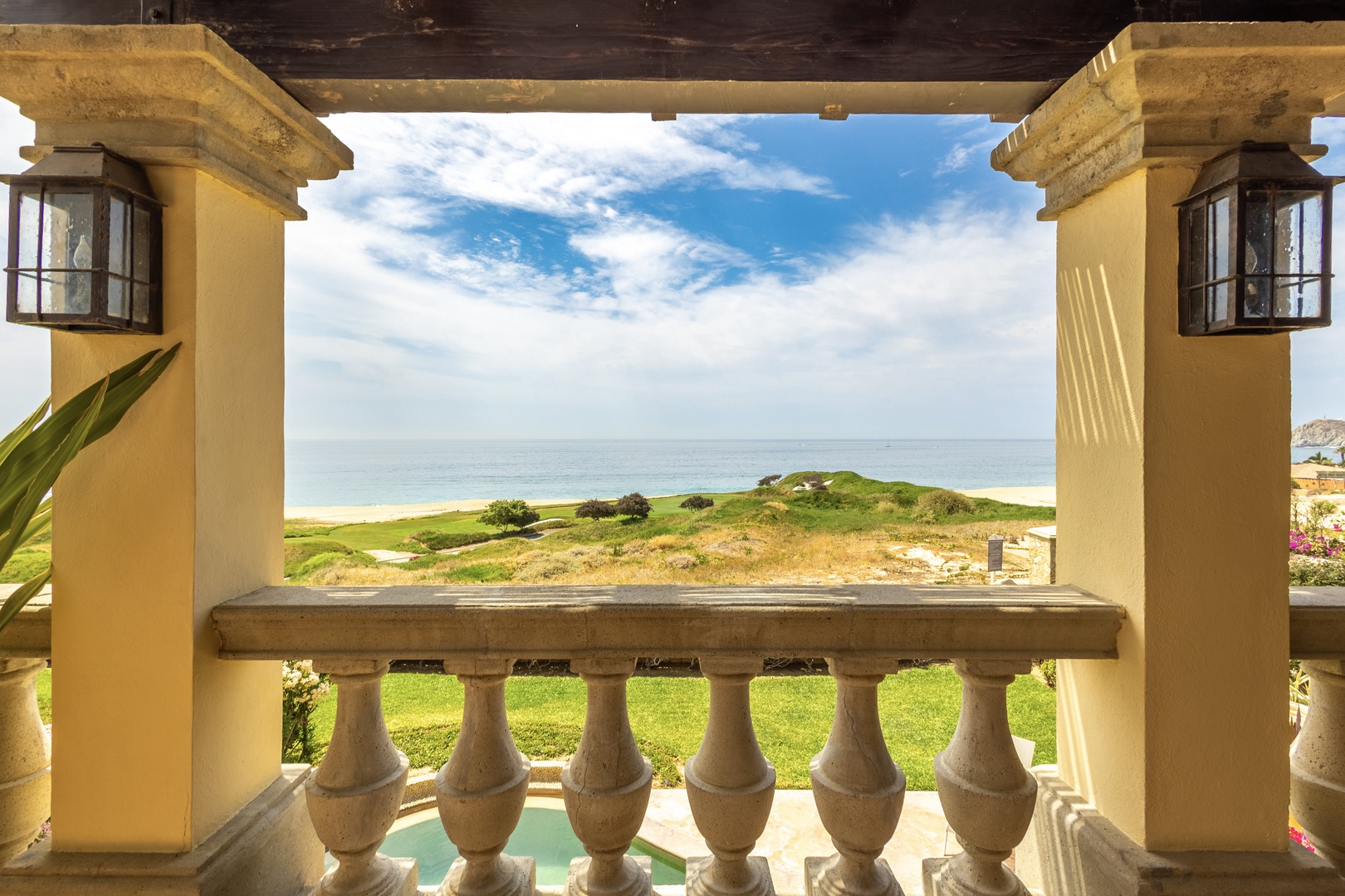 Coastal property featuring architectural details, lush grounds, and panoramic ocean views framed by decorative columns and lanterns.