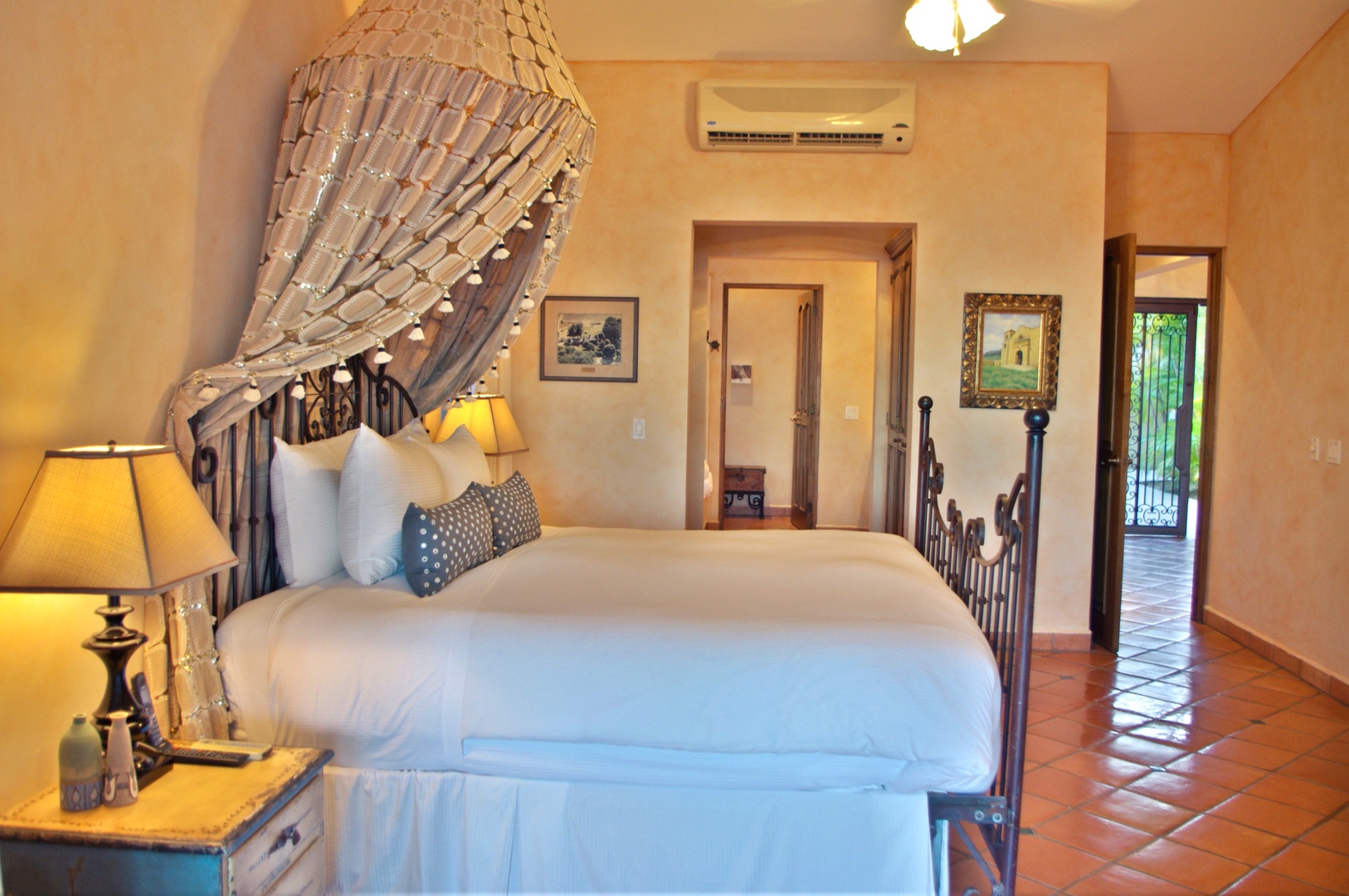 Sink into crisp linens beneath a romantic canopy in your beautifully decorated bedroom, where warm tones and authentic tile floors create your peaceful retreat.