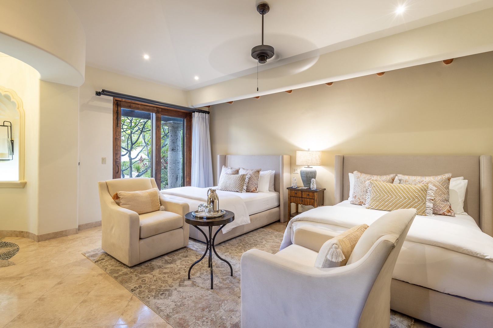 You'll sleep in style with two plush queen beds, elegant seating areas, and soft natural light streaming through tropical garden views.