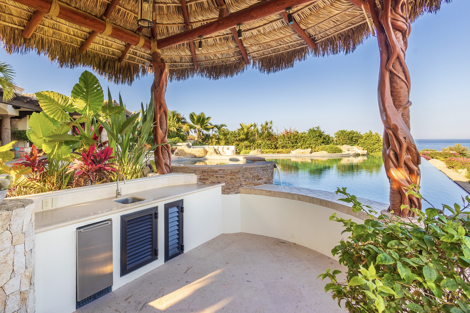 Sip your favorite drink at your outdoor bar while enjoying lush tropical gardens, a sparkling pool with waterfall, and ocean views—all under a charming palapa.