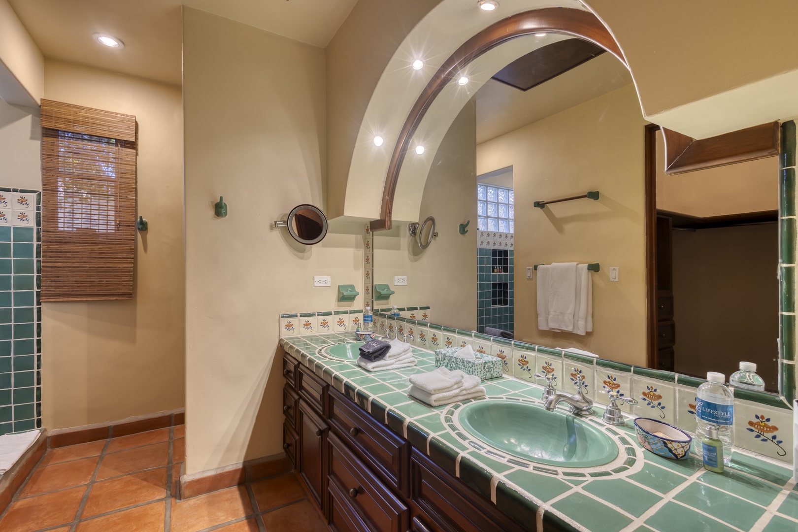 Relax in your beautifully tiled bathroom featuring dual sinks, charming archway, and warm southwestern touches.