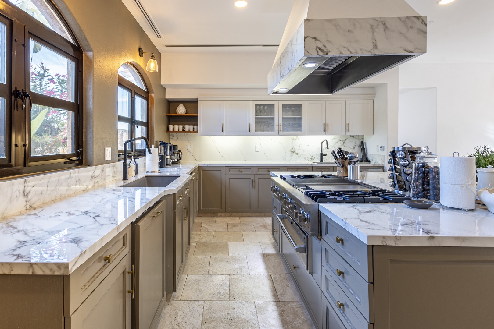 Cook in style with luxurious marble countertops, professional-grade appliances, and abundant natural light streaming through elegant arched windows.
