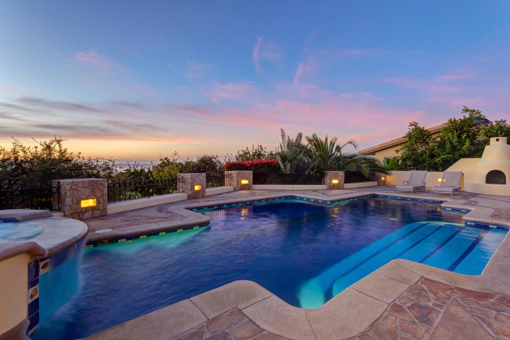Stunning pool area with dramatic sunset skies and elegant stone lighting creating the perfect evening ambiance.