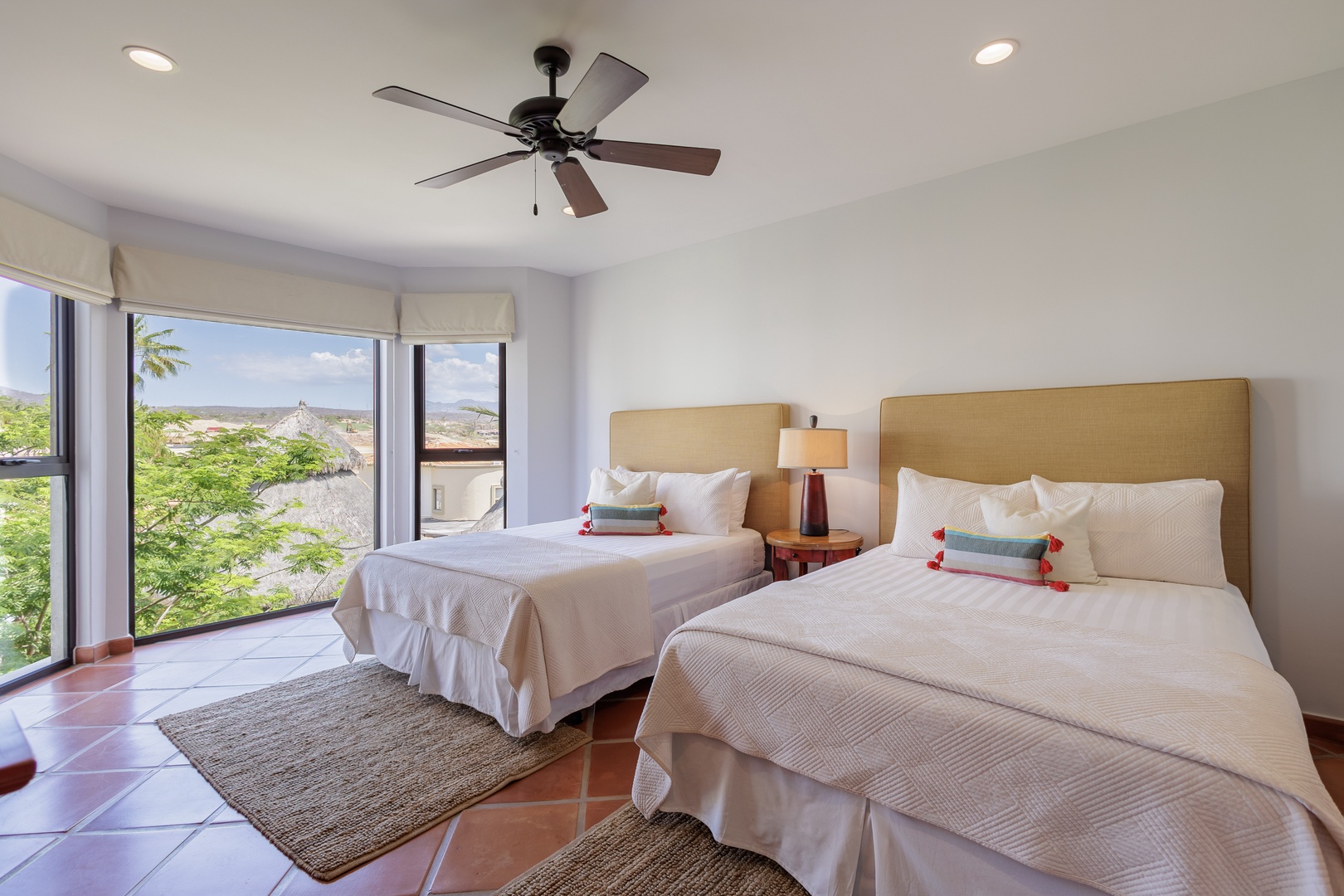 Wake up to natural light and arid landscape views through spacious windows in your serene retreat. Two plush beds, a ceiling fan, and warm tile floors create your restful sanctuary.