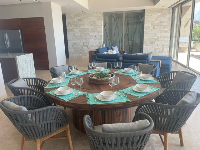 Picture yourself enjoying meals at this stunning round dining table for eight, with sleek modern chairs and elegant place settings. The open-concept space flows seamlessly to a cozy lounge and bright outdoor terrace.