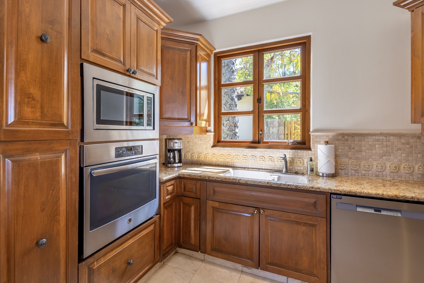 Cook your favorite meals in this well-equipped kitchen featuring rich wood cabinetry, granite countertops, and modern appliances.