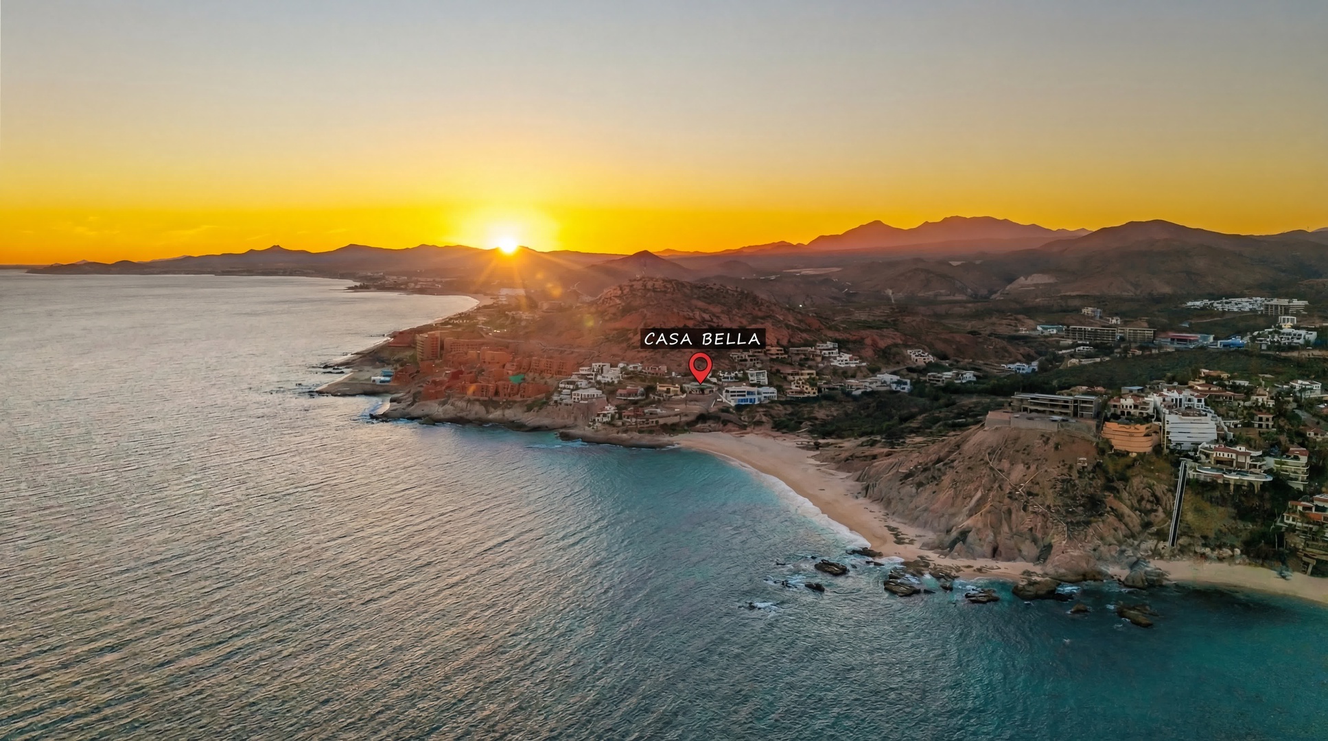 Stunning aerial view of Casa Bella's coastal location at sunset, with pristine beaches and turquoise waters stretching toward distant mountains.