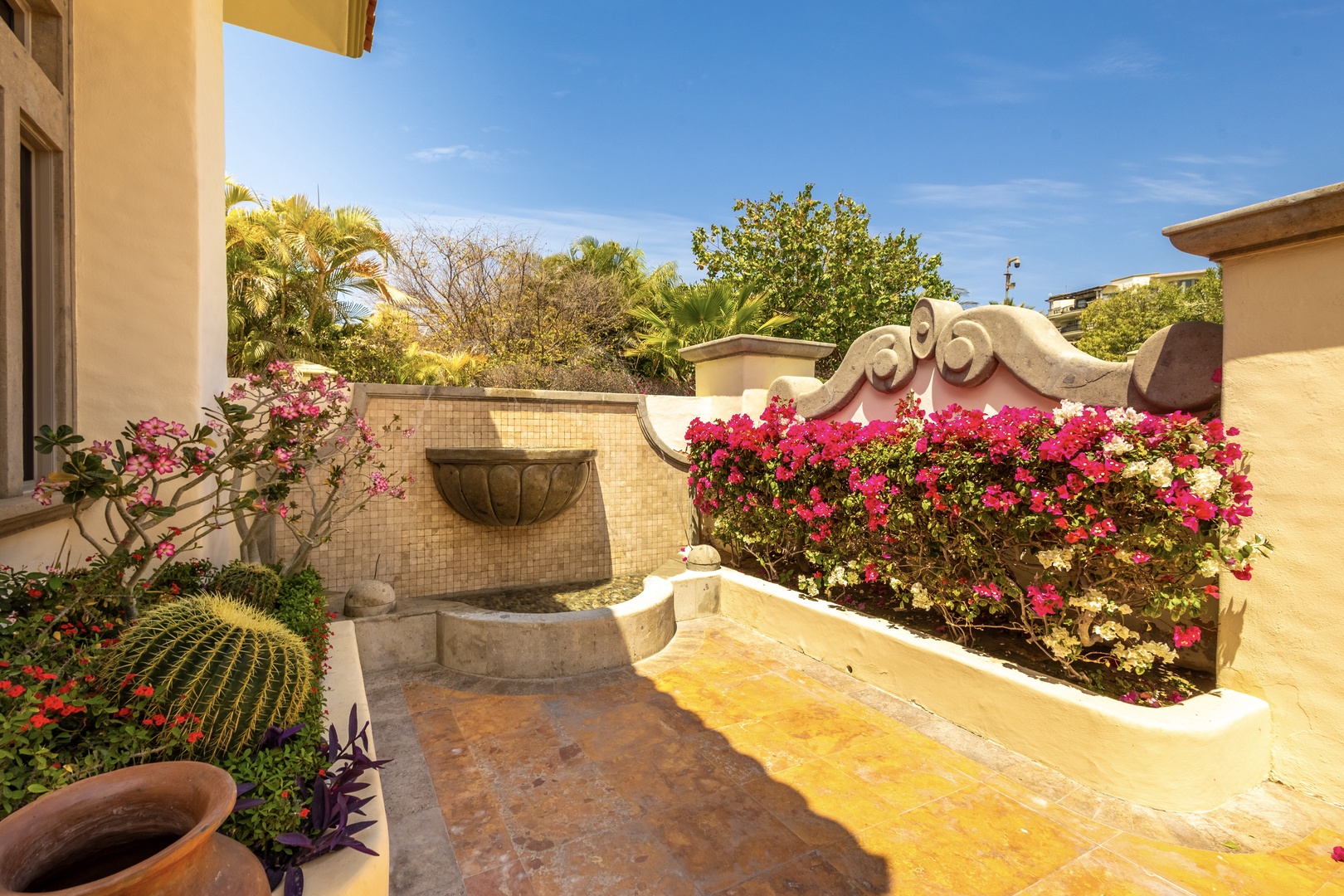 Sunlit courtyard features vibrant bougainvillea cascading over decorative walls, creating a colorful private oasis where you can enjoy peaceful mornings surrounded by lush tropical plantings and elegant architectural details.