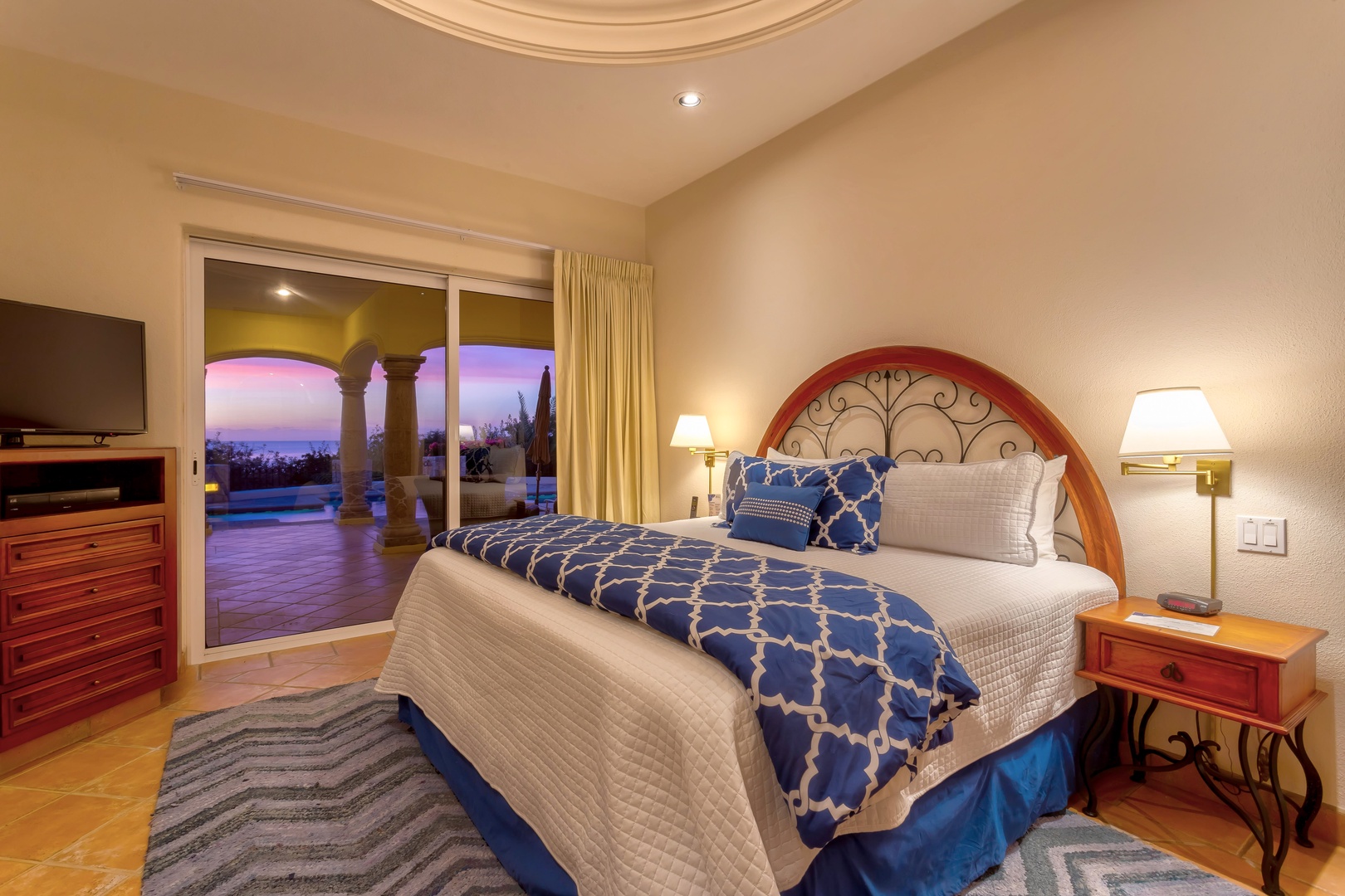 Unwind in your elegant bedroom where warm lighting and luxurious bedding create the perfect retreat after desert adventures.