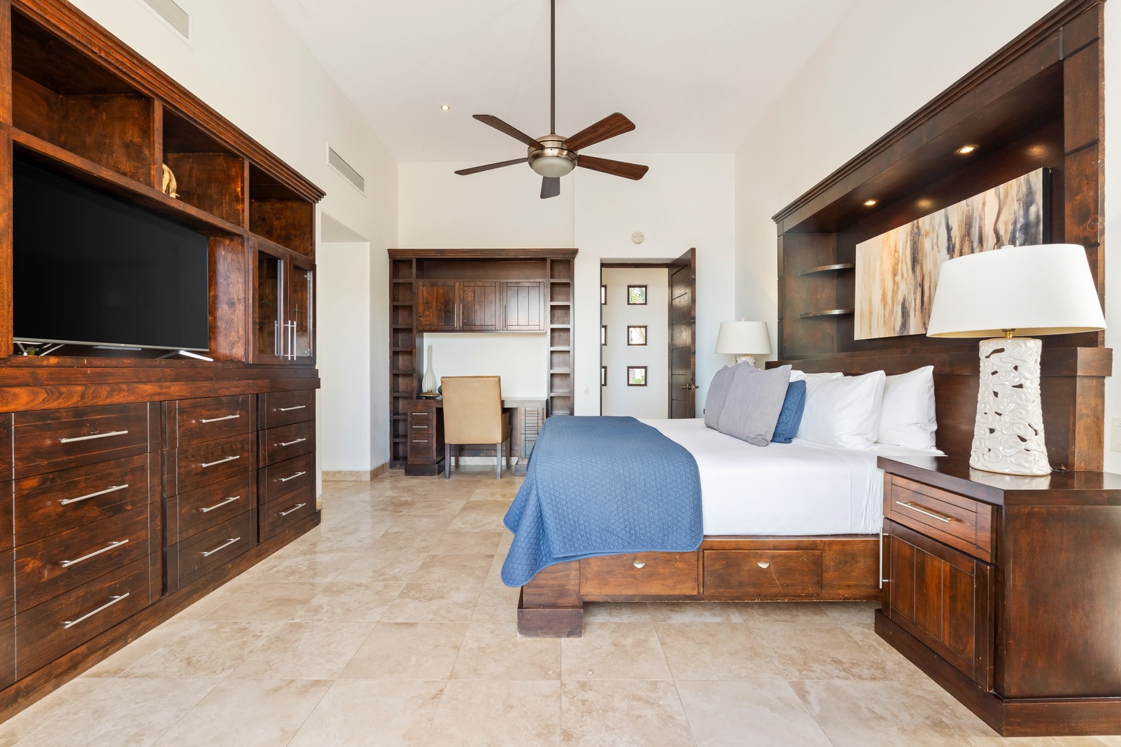 Sink into your luxurious master suite with rich wood furnishings, custom built-ins, and a peaceful blue accent.