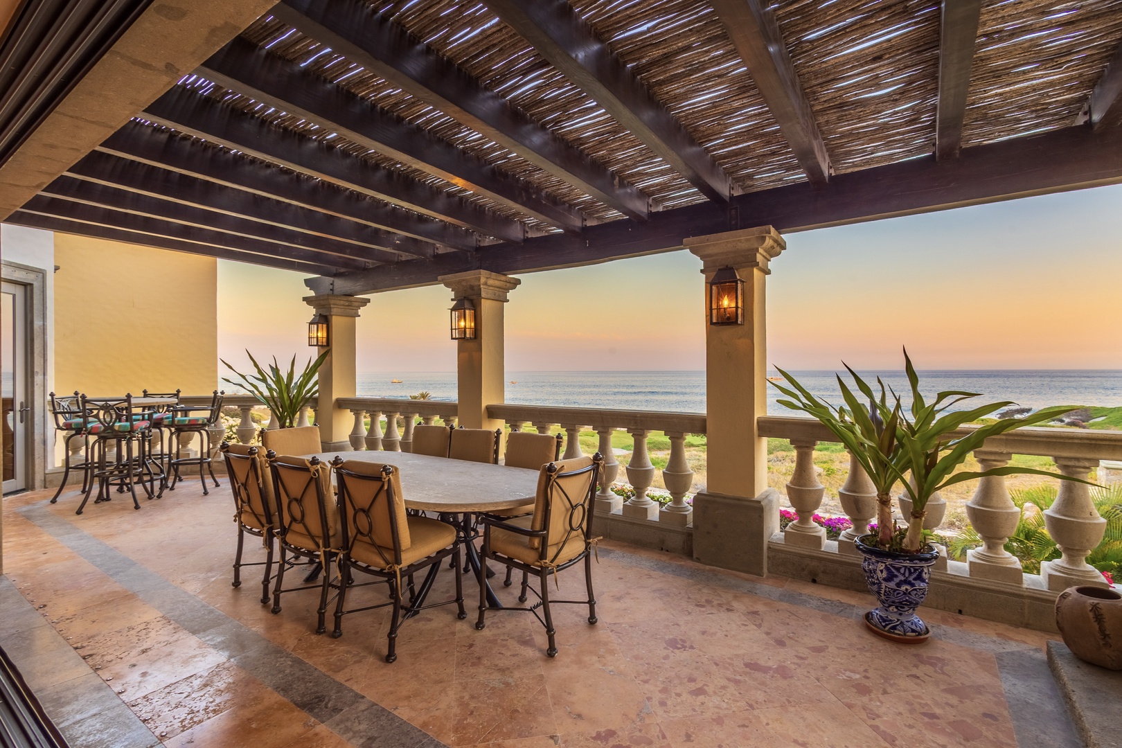 The oceanfront terrace captures stunning sunset views while providing elegant outdoor dining space overlooking pristine coastal greens and the endless sea beyond.