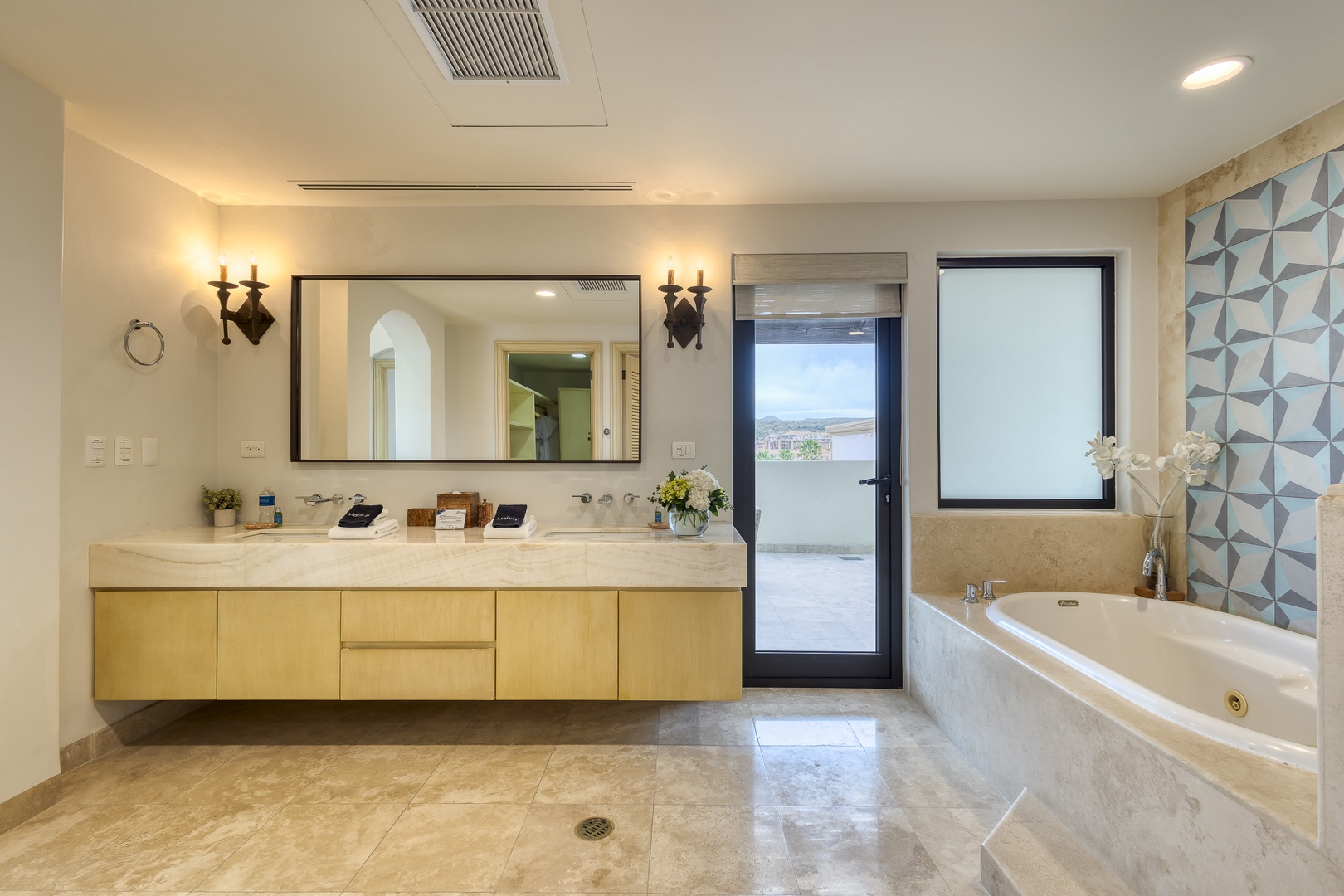 Step into your private spa-like bathroom, where a soaking tub invites you to unwind beneath geometric tile, soft candlelight, and serene natural light.
