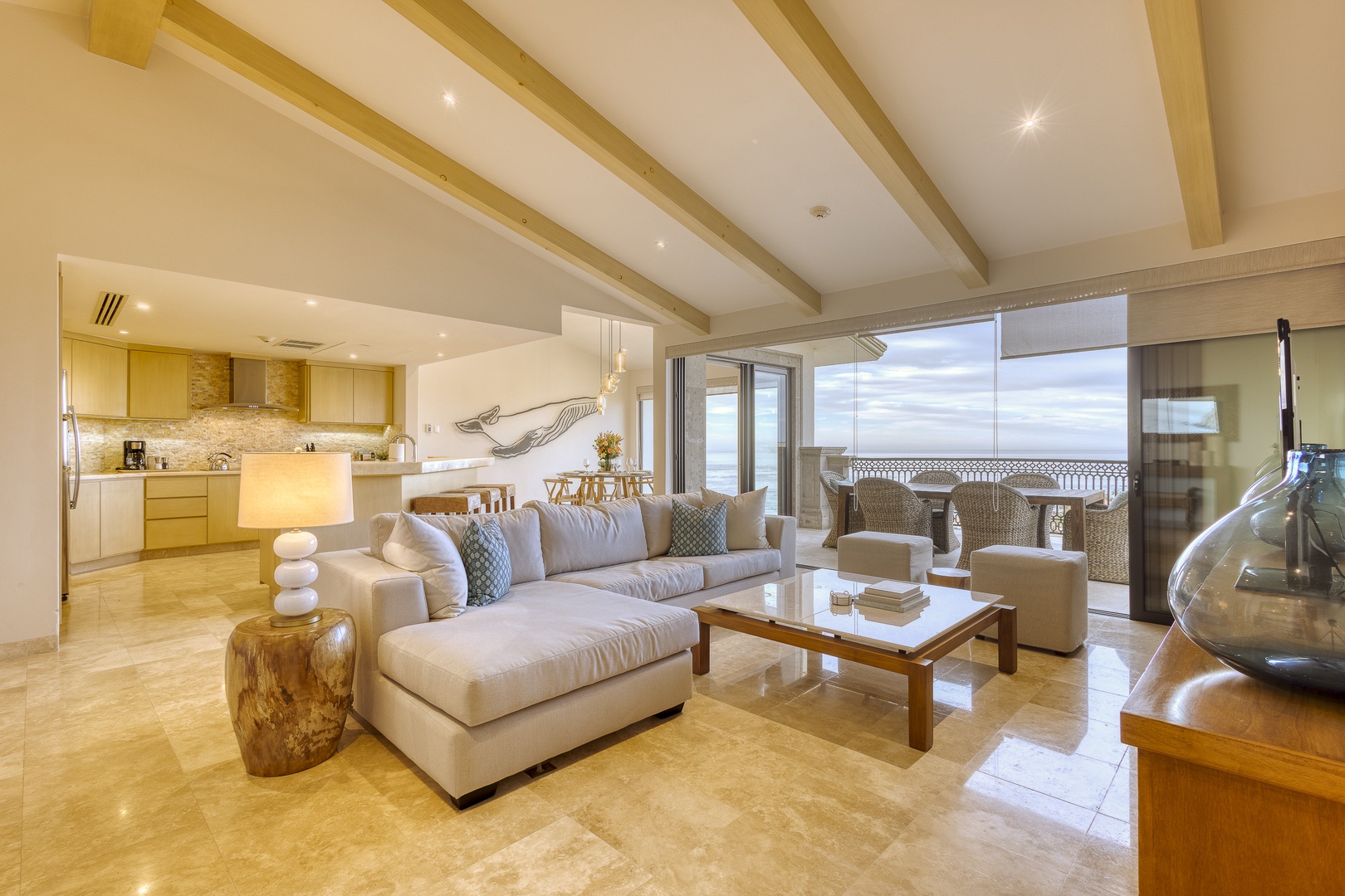 Sink into plush sofas beneath vaulted beams as ocean breezes drift through open balcony doors—your serene coastal retreat awaits.