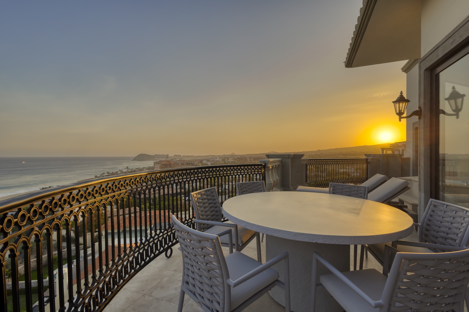 Sunset illuminates the beachfront property terrace with ocean panoramas and elegant coastal dining setup.