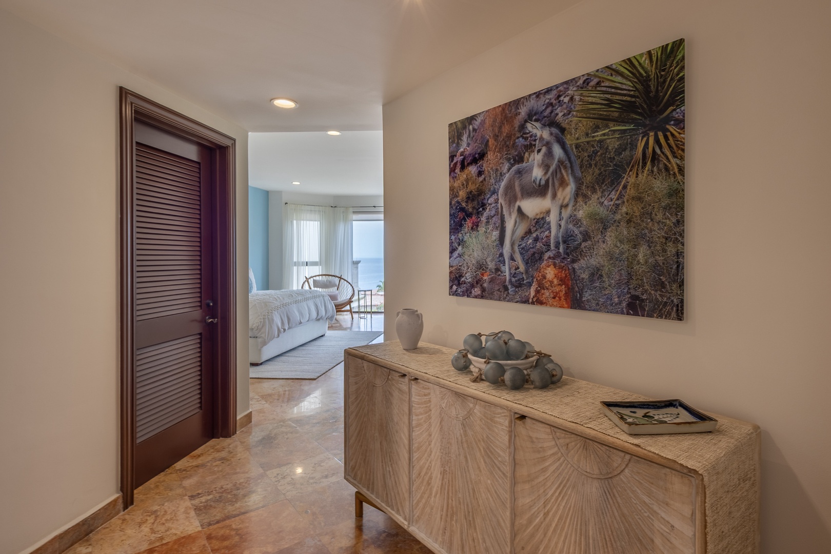 Step into your stylish entryway where warm wood furnishings and vibrant local art create an inviting first impression of your tropical getaway.