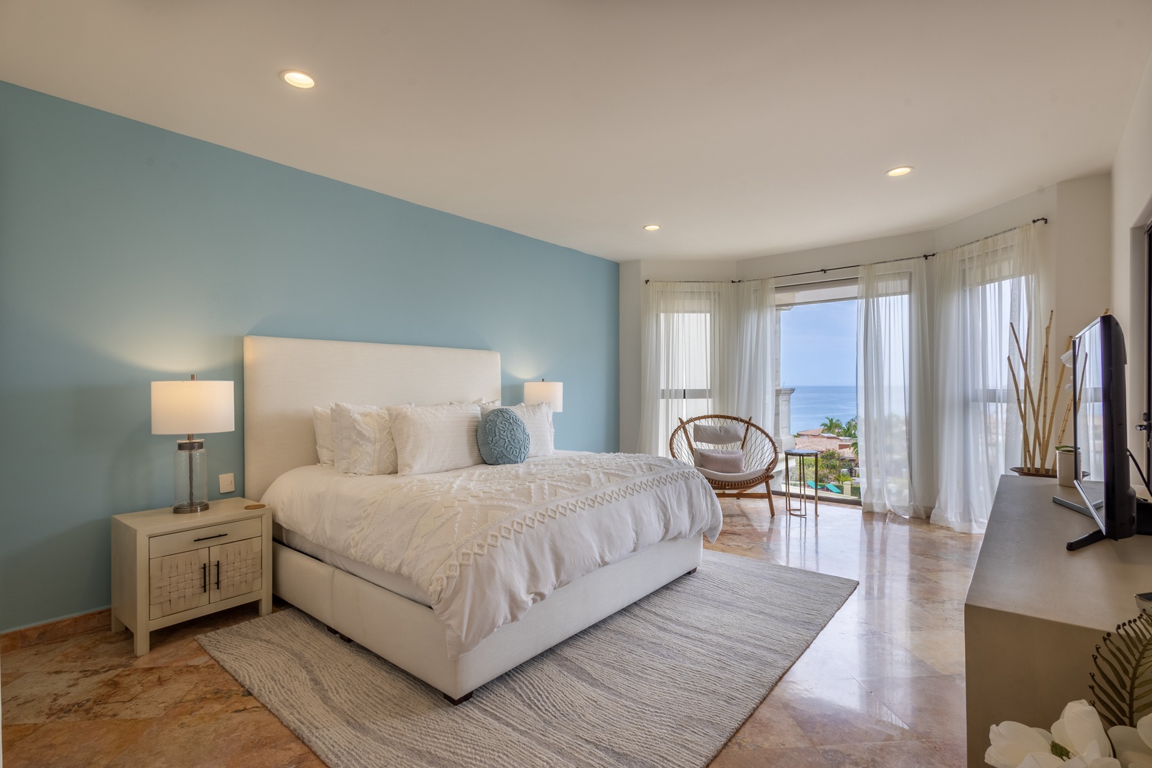 Wake up to stunning ocean views from your king bed in this serene coastal bedroom with calming blue accents.